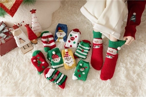 Close-up of cozy coral fleece Christmas socks with festive reindeer and Santa patterns