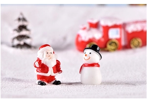 Macro shot of resin Christmas figures featuring Santa and a snowman on white snow scenery