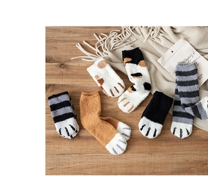 Close-up of thick coral fleece socks with cat paw patterns on a warm wooden surface