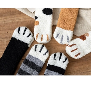 Close-up of cozy cat claw coral fleece socks in various patterns on wooden background