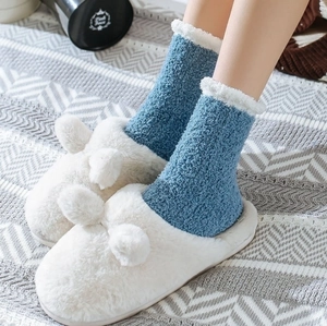 Close-up of blue coral fleece socks with white faux fur trim and plush slippers