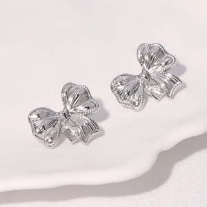 Elegant silver bow stud earrings in stainless steel on white ceramic plate