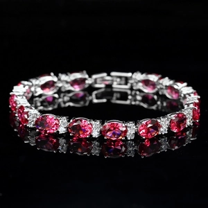 Macro shot of a luxury tennis bracelet featuring oval rubies and white zirconias on black surface