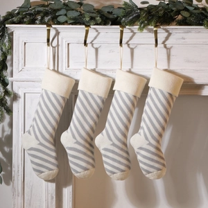 Set of 4 knitted Christmas stockings with grey stripes and cream cuffs on a mantel