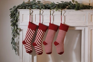 Close-up of four red and white striped knitted Christmas stockings on a white fireplace