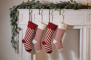 Close-up of four red and white diagonal striped knit Christmas stockings on a mantel