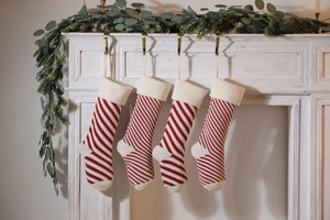 Detail of red and white striped knit Christmas stockings hanging on a white wooden mantel