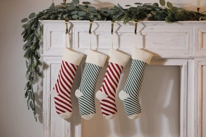 Close-up of knitted striped Christmas stockings hanging on a white fireplace mantle