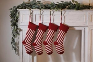 Close-up of four red and white striped knitted Christmas stockings on a white mantel