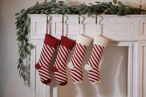 Detail showing four red and white striped knitted Christmas stockings on a white fireplace