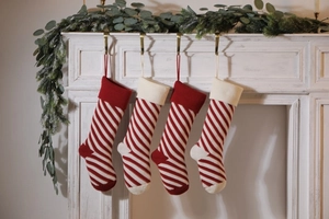 Close-up of red and white striped knitted Christmas stockings hanging on a white fireplace