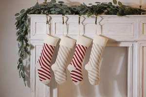 Set of four knitted Christmas stockings with red and white diagonal stripes hanging on mantel