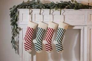 Detail of red and green striped knitted Christmas stockings hanging on a white mantel