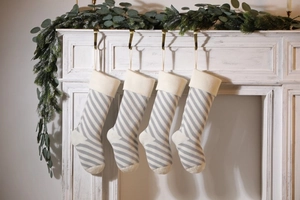 Detailed view of four grey and white striped knitted Christmas stockings on a mantel