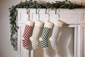 Close-up of four knitted striped Christmas stockings hanging on a white fireplace mantle