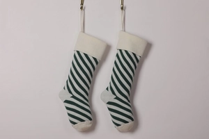 Detail of green and white striped knitted Christmas stockings hanging on a white wall