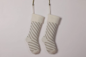 Detail of hanging knitted Christmas stockings with beige and grey diagonal stripe patterns