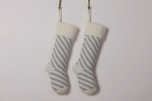 Close-up of grey and white striped knitted Christmas stockings with beige cuffs and toes