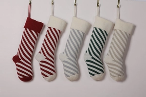 Row of five knitted Christmas stockings with red, green and grey stripes on white backdrop