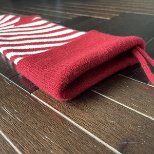 Close-up of red and white striped knitted Christmas stocking on dark wood background