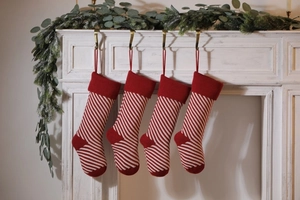 Detail of red and white striped knitted Christmas stockings hanging on a white fireplace