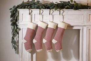 Close-up of red and white striped knitted Christmas stockings hanging on a white fireplace