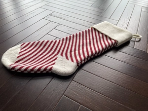 Macro detail of red and white striped knitted Christmas stocking on wooden floor