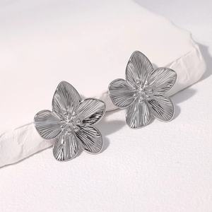 Macro shot of silver flower earrings with realistic petal textures on a white stone base