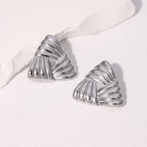 Minimalist silver triangle stud earrings with textured radial stripes on stone background