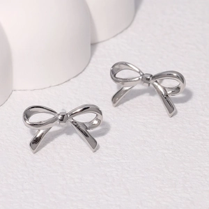 Minimalist polished silver bow knot stud earrings on a clean white textured background
