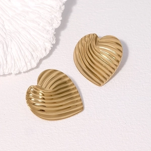 Golden heart-shaped stud earrings with textured wavy pattern on minimalist background