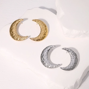 Textured crescent moon stud earrings in gold and silver finish on white stone