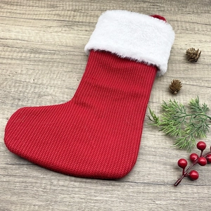 Classic red knitted Christmas stocking with white faux fur cuff on wood background