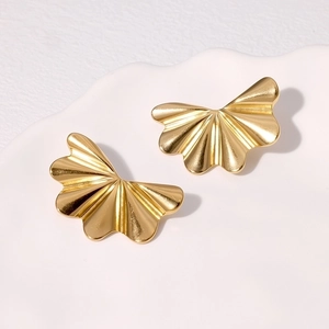 Elegant gold fan-shaped stud earrings with pleated texture on white ceramic plate