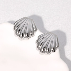 Macro detail of silver shell-shaped earrings with polished metallic radial texture