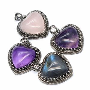 Natural quartz heart pendants set with vintage silver bezel settings on white surface