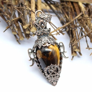Close-up of a drop-shaped tiger eye stone pendant in a silver vintage filigree frame