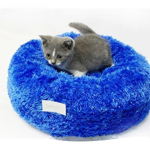 Close-up of fluffy long-hair deep blue pet bed with raised edges and a kitten inside