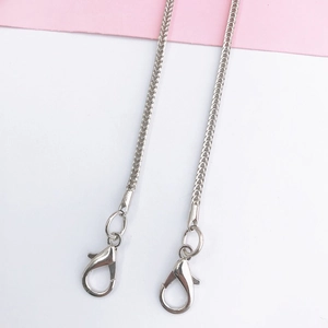 Detail of silver woven metal phone chain strap with lobster clasps on two-tone background