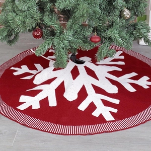 Detail of red knit Christmas tree skirt featuring large white snowflake pattern and texture