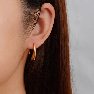 Elegant gold teardrop earrings in polished stainless steel worn by a fashion model