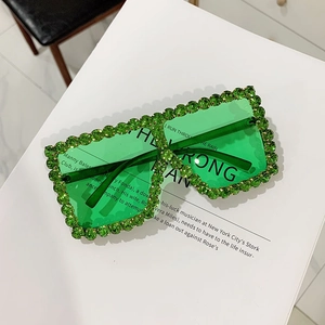 Detail of green oversized square sunglasses with rhinestones on a white book