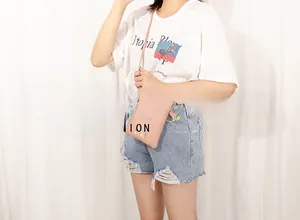 Pink leather phone bag with cactus embroidery worn by model over a white T-shirt