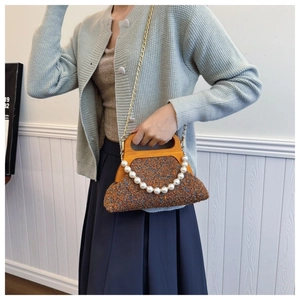 Retro tweed handbag detail with wooden handle, pearl accent, and gold chain strap