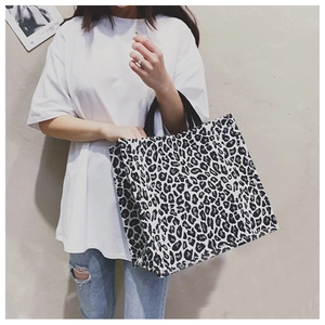 Spacious leopard print tote bag with black handles shown on a model in daily use