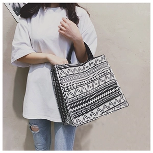 Close-up of a canvas tote bag with black and white tribal geometric patterns and handles