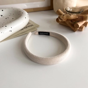 Detailed shot of beige handmade sponge headband with woven fabric texture and label