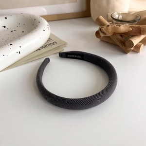 Detail of dark gray sponge headband with ribbed texture and black handmade woven label