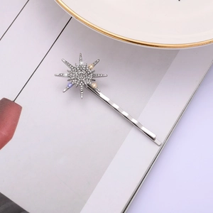 Barrette à cheveux argentée en forme d'étoile avec strass brillants sur un magazine