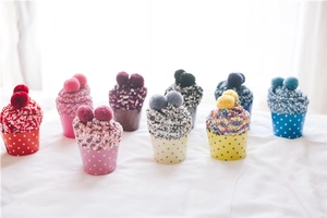 Close-up of fluffy coral fleece socks in creative cupcake gift packaging with pom-poms